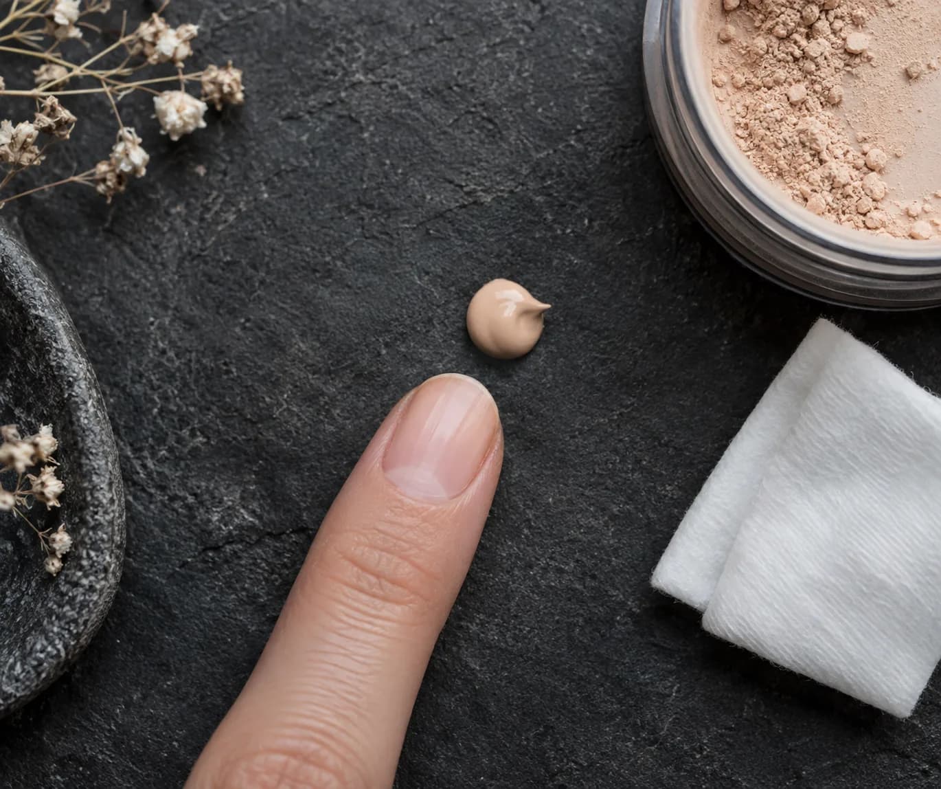 Kleiner Tropfen Augen-Base neben sauberer Fingerspitze und gefaltetem Pad auf dunklem Stein