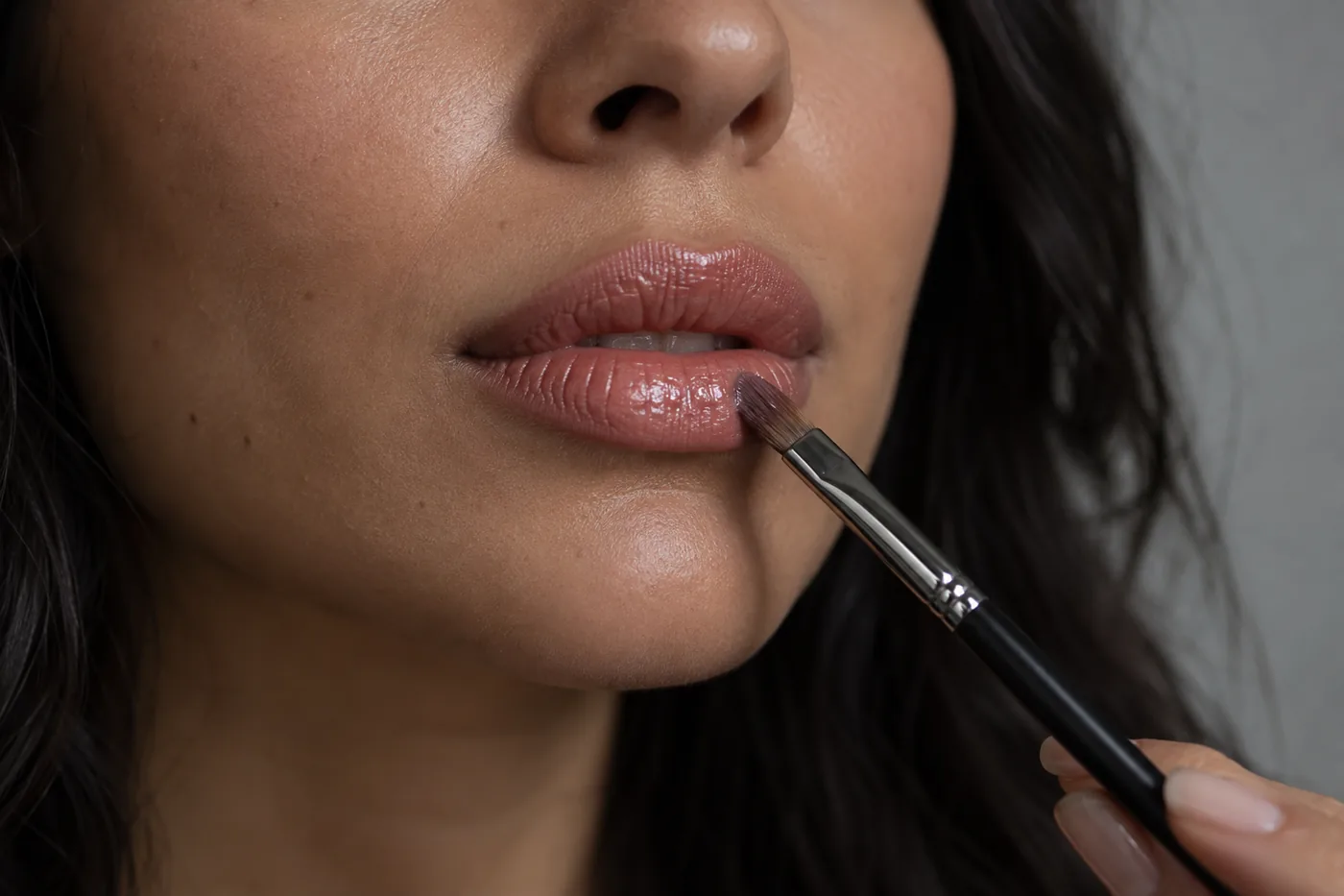 Sauberer kleiner Lippenpinsel setzt zurückhaltenden Glanz auf gedämpft roséfarbene Lippen mit sichtbaren natürlichen Linien