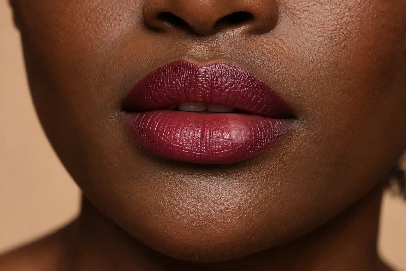 Primer plano de labios adultos en piel marrón oscura con color baya, pliegues naturales y una zona más clara y reflectante en el labio inferior