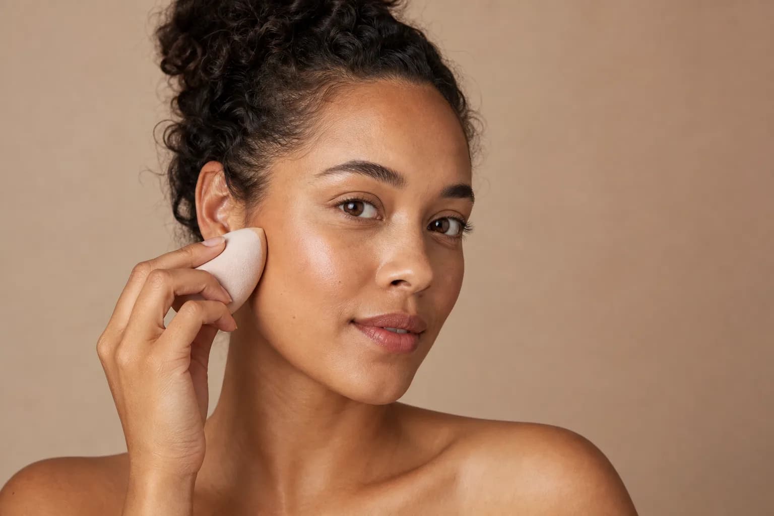 Woman pressing a makeup sponge over a lightweight, skin-like foundation finish