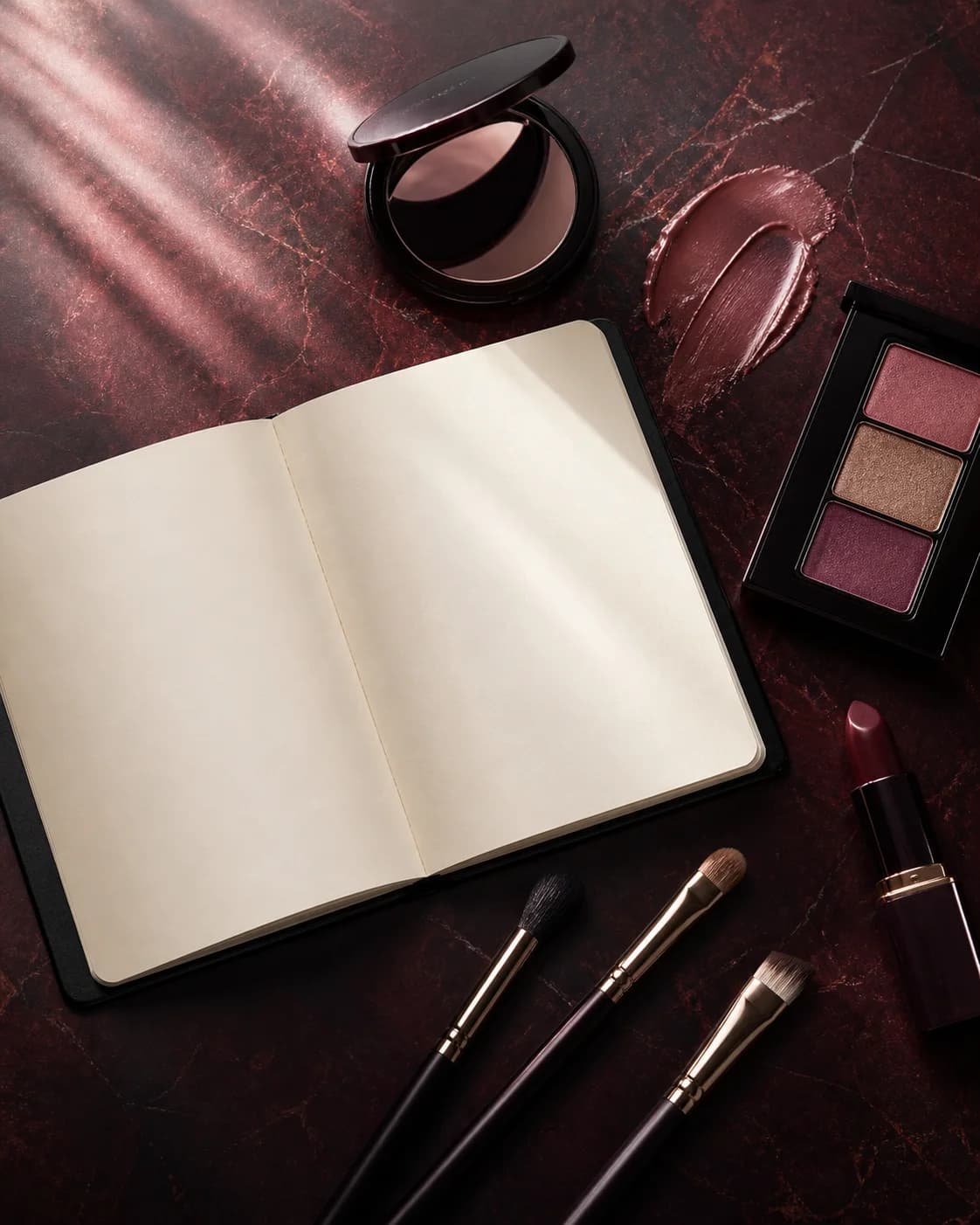 Blank makeup notebook, palette, brushes, and lipstick arranged for routine planning